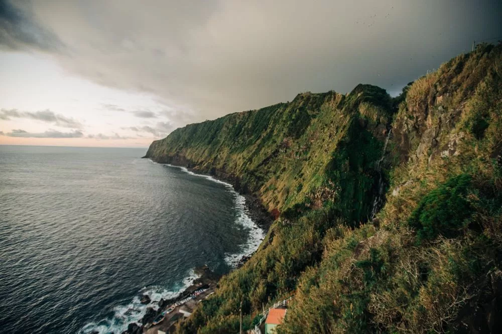 A breathtaking view of the Azores coastline with emerald-green landscapes meeting the Atlantic Ocean