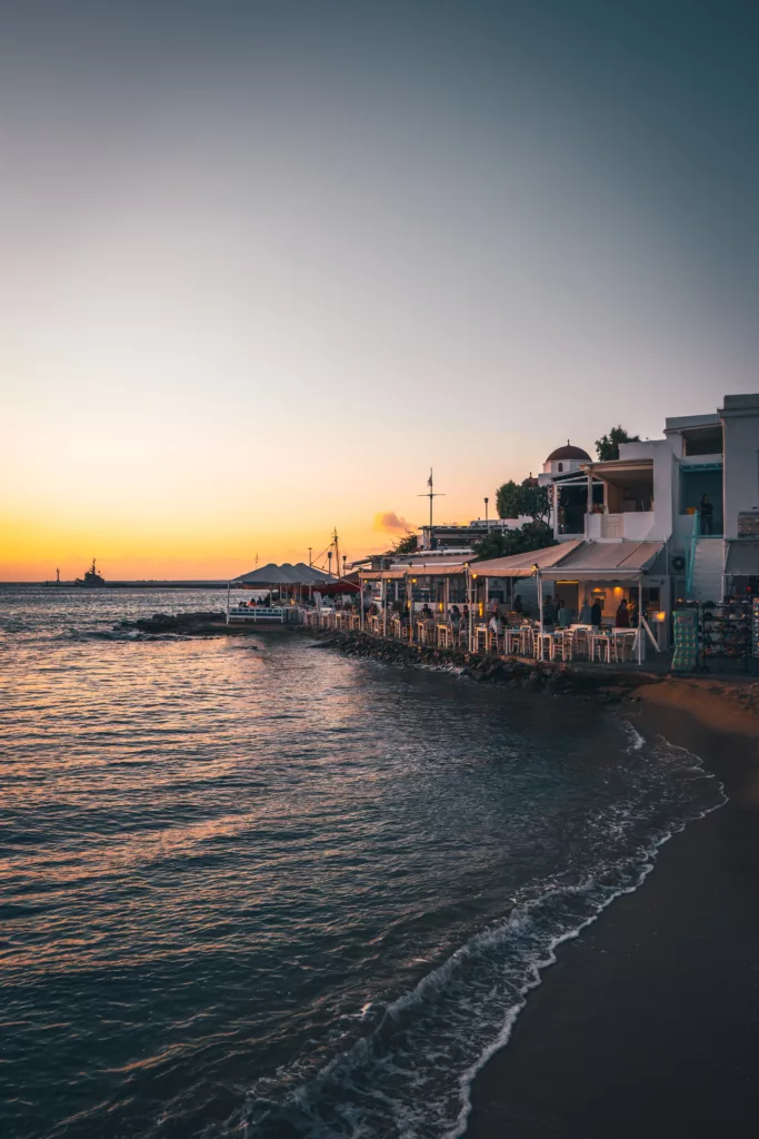 A mesmerizing Mykonos sunset over the Aegean Sea, with the sun casting a warm glow on the horizon and reflecting off the tranquil waters.