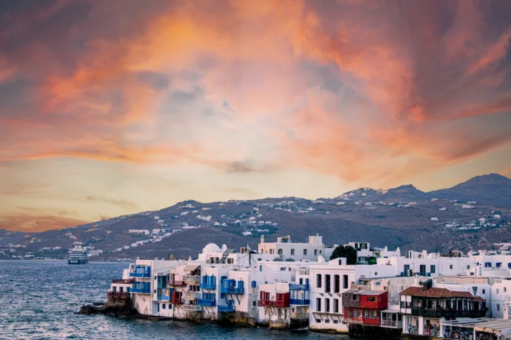 A breathtaking cityscape view of Mykonos, Greece, overlooking the charming white-washed buildings nestled along the seaside, with the azure waters of the Aegean Sea in the background.